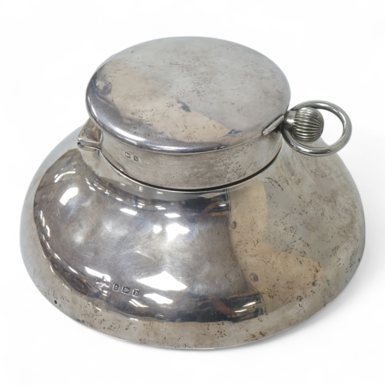 An Edwardian silver circular inkwell, the hinged cover inset with an 8-day open faced pocket watch, with Roman dial and subsidiary seconds, makers mark rubbed, Saunders & Shepherd?, Birmingham, 1907, diameter of the base